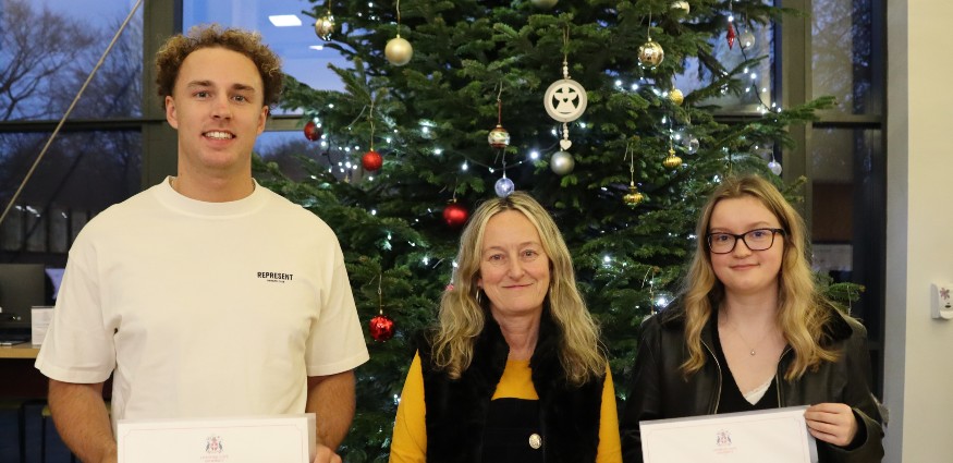 A man and two women stand in front of a Christmas tree.